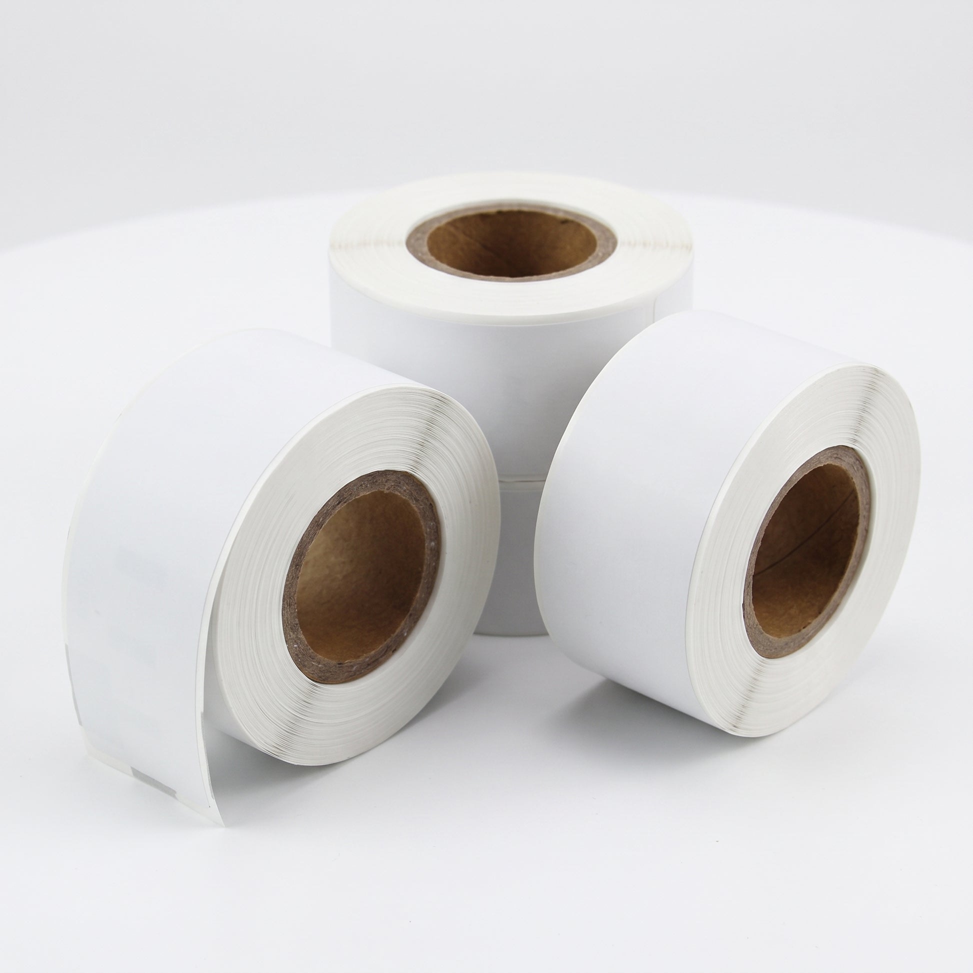 Three rolls of white label paper on a light gray background